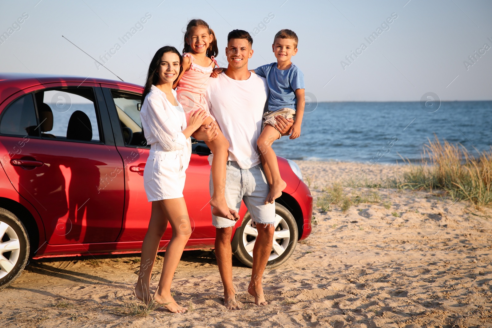 Photo of Happy family near car on sandy beach. Summer trip