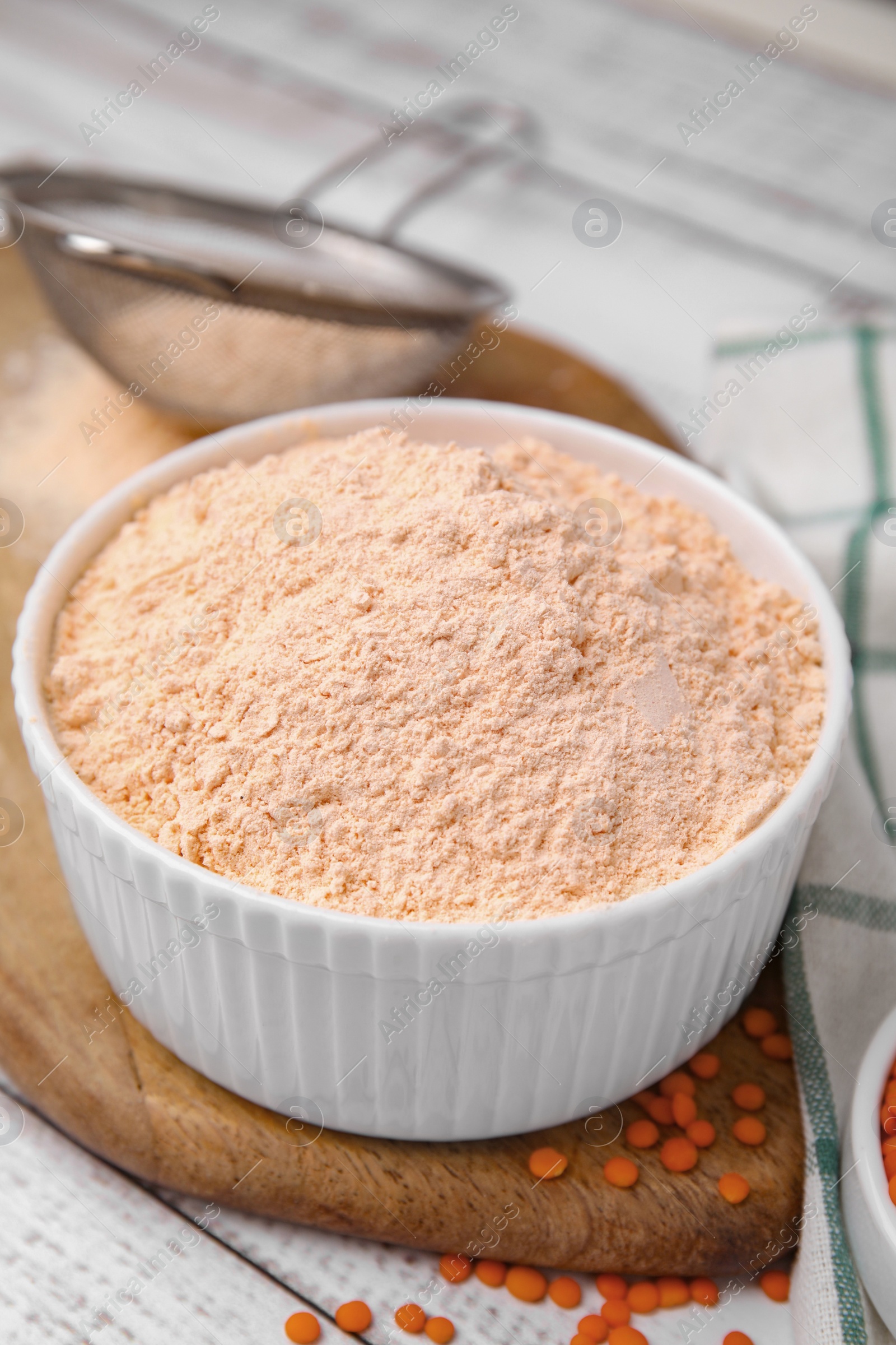 Photo of Bowl of lentil flour and seeds on white wooden table