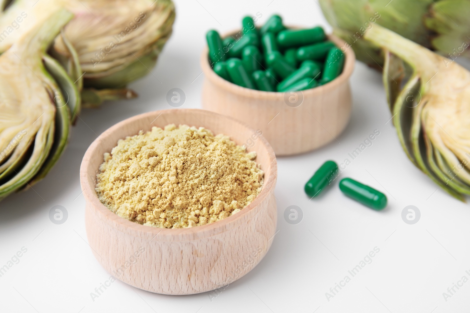 Photo of Bowls with pills, powder and fresh artichokes on white background, closeup