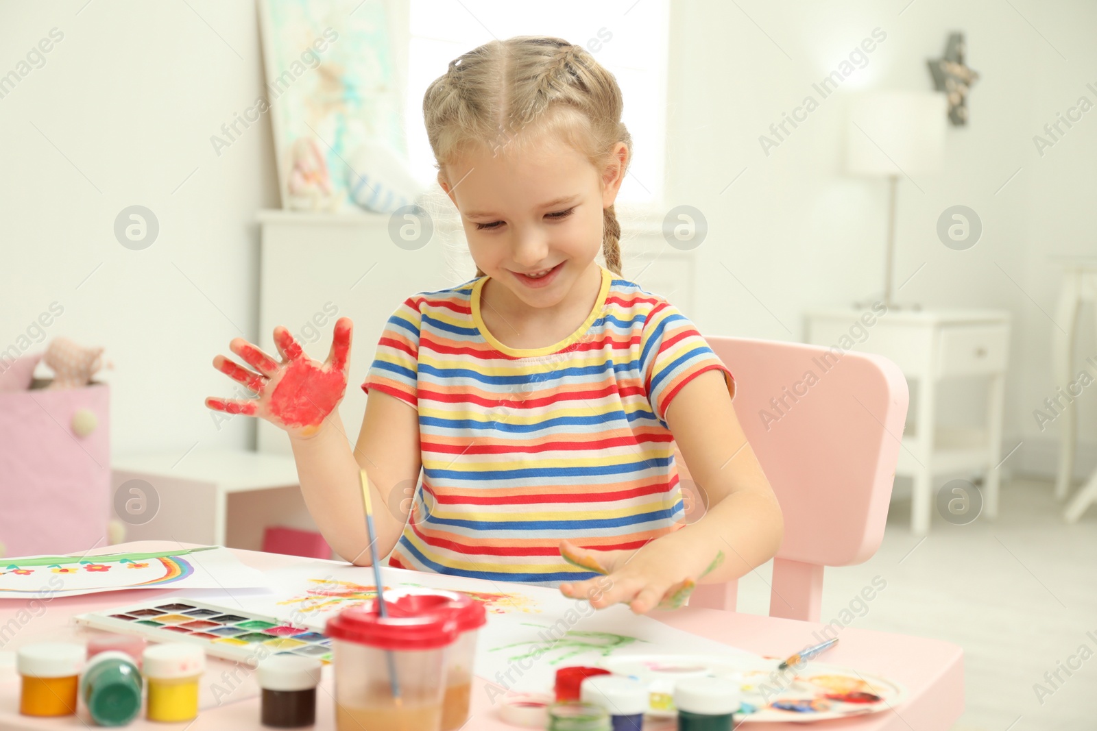 Photo of Cute little child painting with palms at table