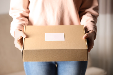 Photo of Woman with closed cardboard box at home, closeup