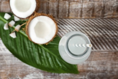 Photo of Bottle of coconut water and fresh nuts on wooden table, top view