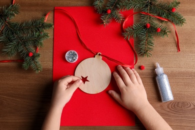 Photo of Little child making Christmas card on wooden table, top view