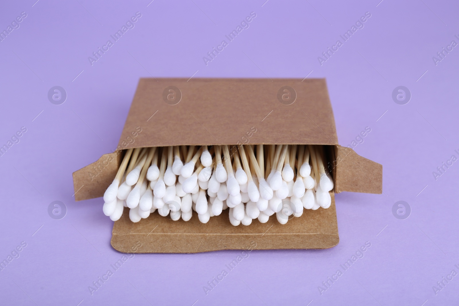 Photo of Box with wooden cotton buds on violet background