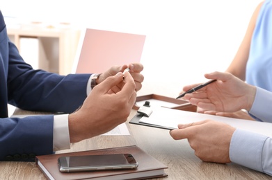 Photo of Lawyer working with clients at table in office, focus on hands