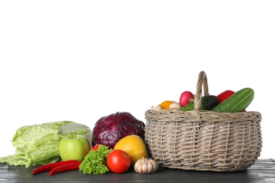 Photo of Wicker basket with variety of fresh delicious vegetables and fruits on table against white background