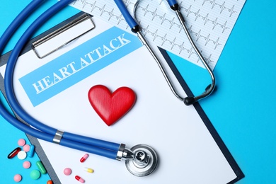 Flat lay composition with stethoscope, clipboard, pills and wooden heart on color background