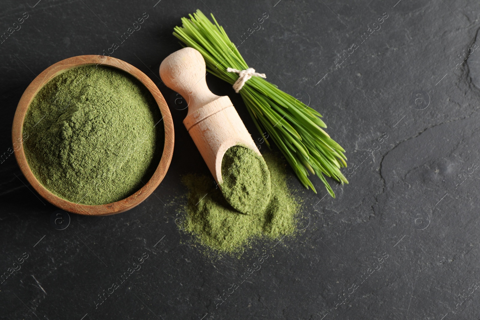 Photo of Wheat grass powder and fresh sprouts on grey textured table, flat lay. Space for text