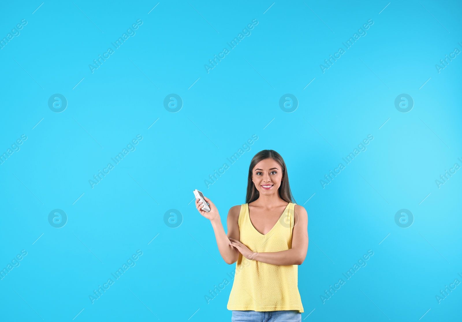 Photo of Young woman with air conditioner remote on color background