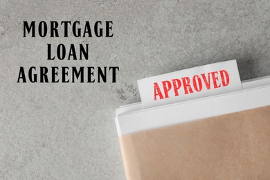 Image of Mortgage loan agreement. Note with Approved stamp in documentation on light grey table, top view