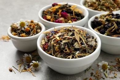 Photo of Different dry aromatic teas on light grey table, closeup