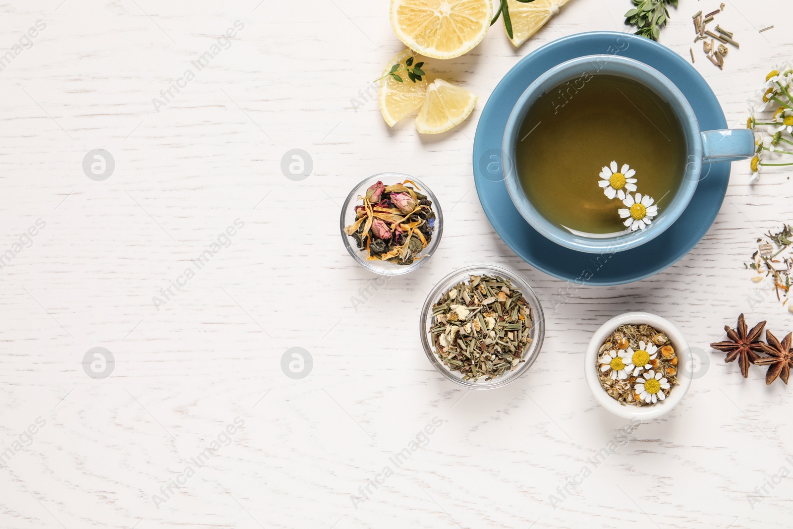 Photo of Flat lay composition of freshly brewed tea with chamomile flowers and dry leaves on white wooden table. Space for text