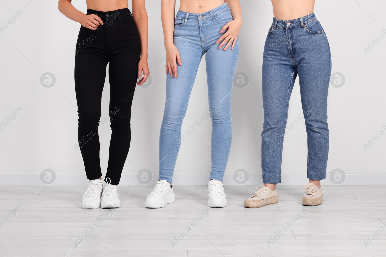 Photo of Women in stylish jeans near white wall, closeup