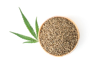 Bowl of hemp seeds with green leaf on white background, top view