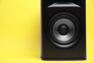 Photo of One wooden sound speaker on yellow background, closeup. Space for text