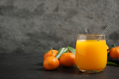 Photo of Glass of fresh tangerine juice and fruits on black table. Space for text