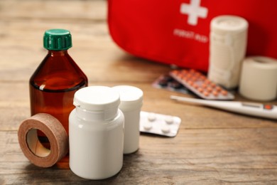 Photo of Medicaments and sticking plaster roll on wooden table, space for text. First aid kit