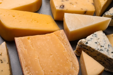 Photo of Different kinds of delicious cheese on stone background, closeup