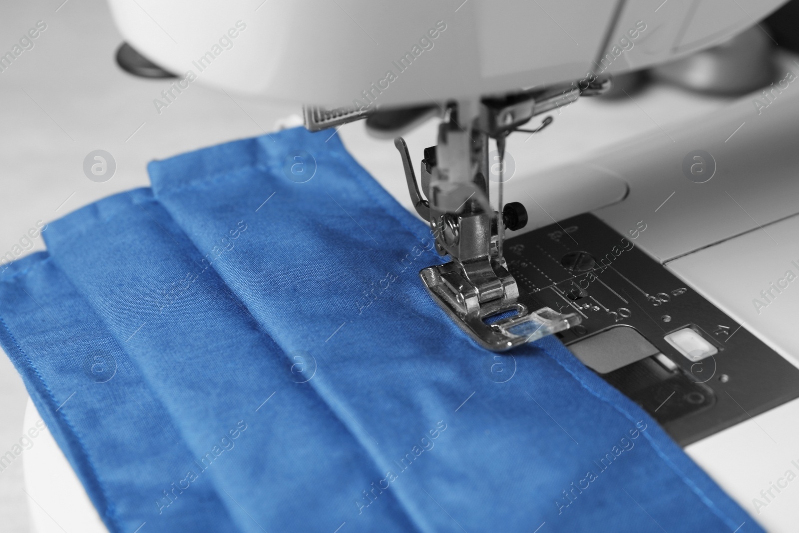 Photo of Sewing machine with homemade protective mask, closeup