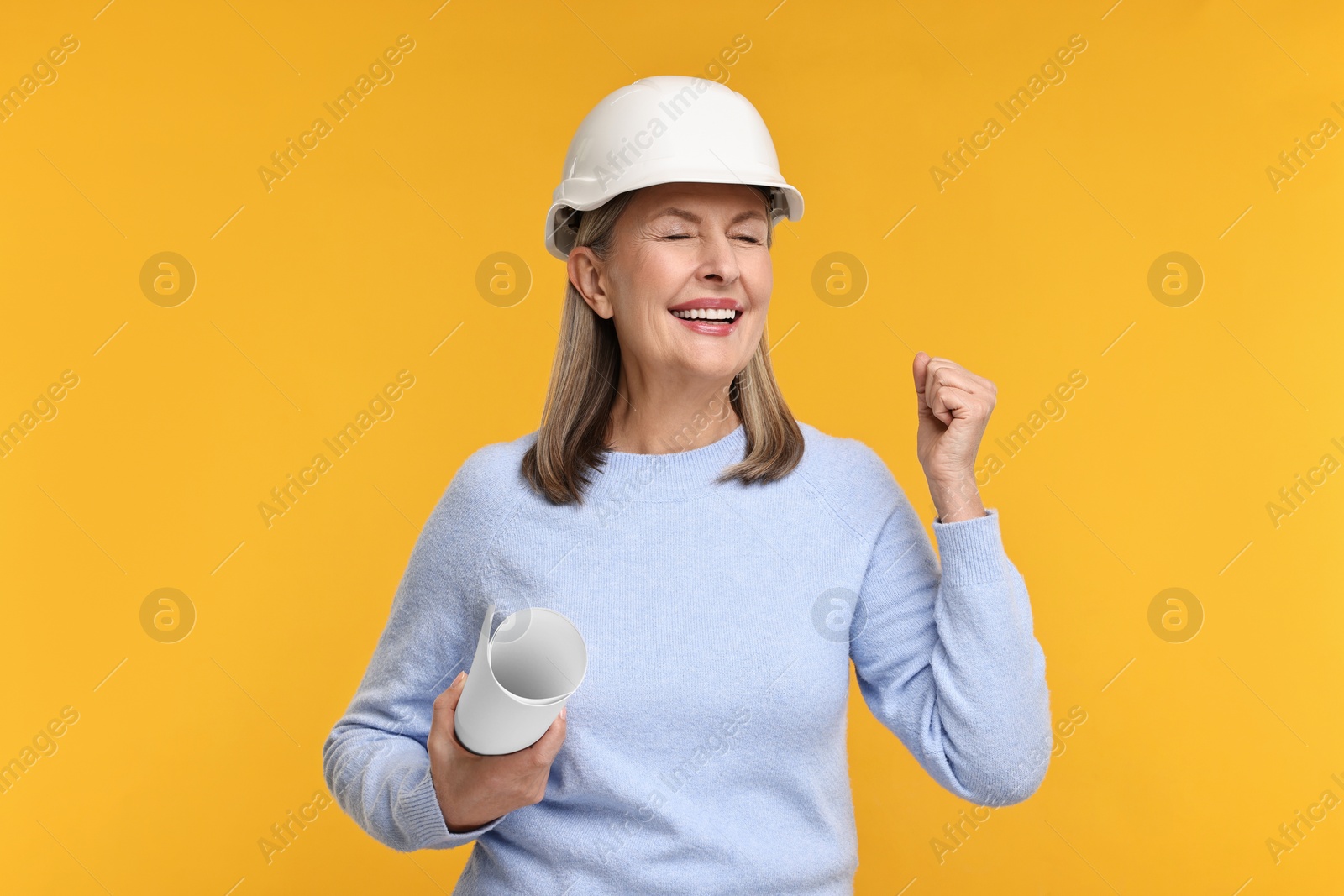 Photo of Architect in hard hat with draft on orange background