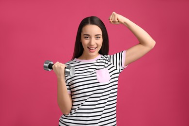 Woman with dumbbell as symbol of girl power on pink background. 8 March concept