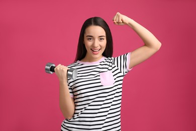 Photo of Woman with dumbbell as symbol of girl power on pink background. 8 March concept