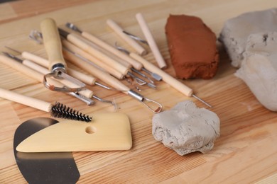 Clay and set of modeling tools on wooden table, closeup