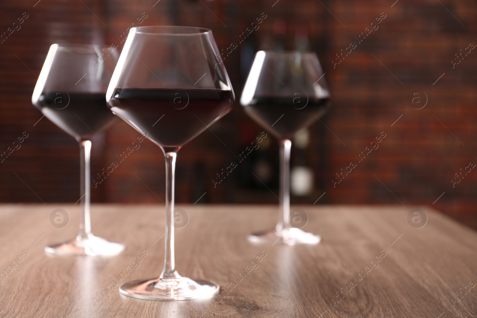 Photo of Tasty red wine in glasses on wooden table, space for text