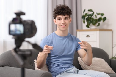 Photo of Smiling teenage blogger explaining something while streaming at home