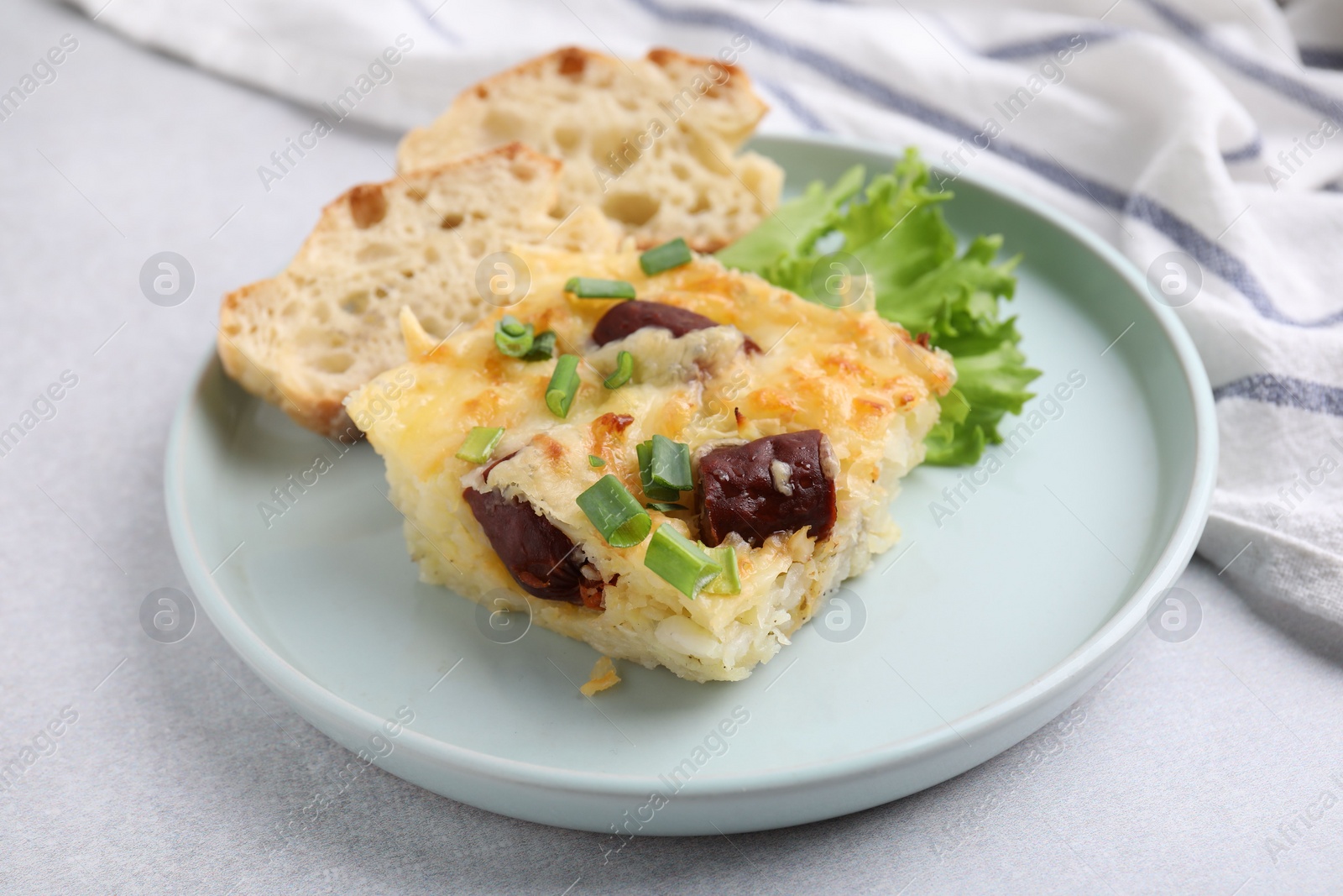 Photo of Tasty sausage casserole with green onion and bread on light grey table