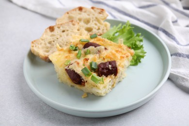 Photo of Tasty sausage casserole with green onion and bread on light grey table