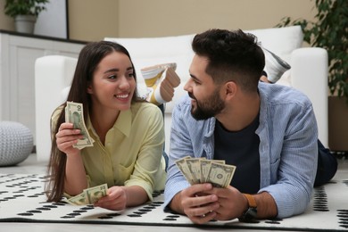 Photo of Happy couple with money on floor at home