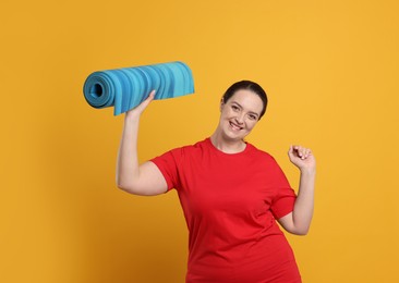 Photo of Happy overweight woman with yoga mat on orange background