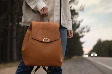 Young woman with stylish backpack walking along road, closeup. Space for text