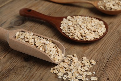 Photo of Scoop and spoons with oatmeal on wooden table, closeup