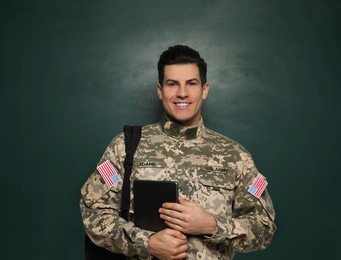 Photo of Cadet with backpack and tablet near chalkboard. Military education