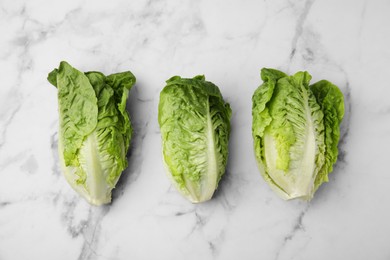 Photo of Fresh green romaine lettuces on white marble table, flat lay