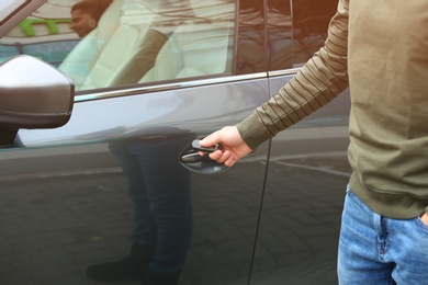 Closeup view of man opening car door with remote key