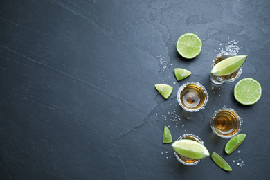 Photo of Mexican Tequila shots with salt and lime slices on grey table, flat lay. Space for text