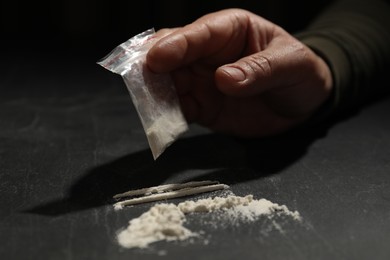 Photo of Drug addiction. Man with cocaine at grey textured table, closeup