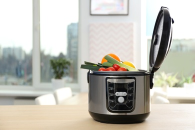 Photo of Modern multi cooker with ingredients on table in kitchen. Space for text