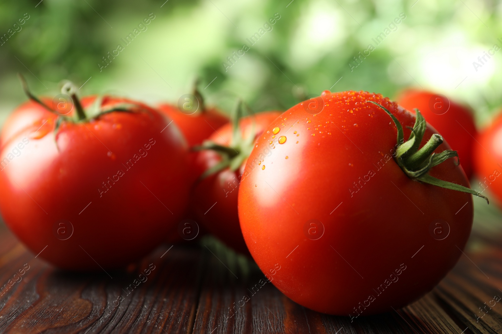 Photo of Fresh ripe tomatoes on wooden table, closeup