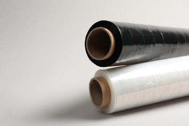 Photo of Rolls of different stretch wrap on light grey background, closeup. Space for text