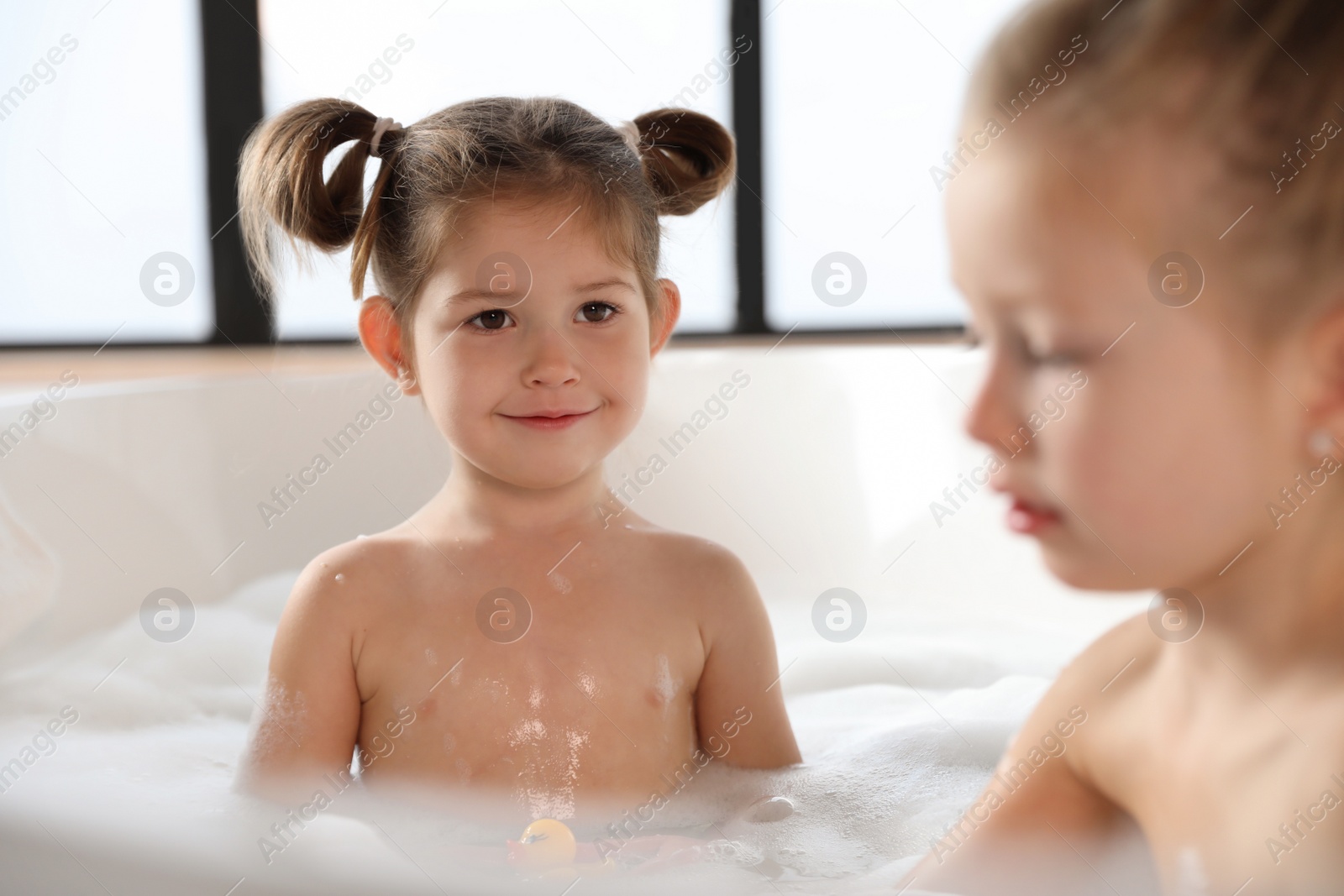 Photo of Cute little sisters taking bubble bath together