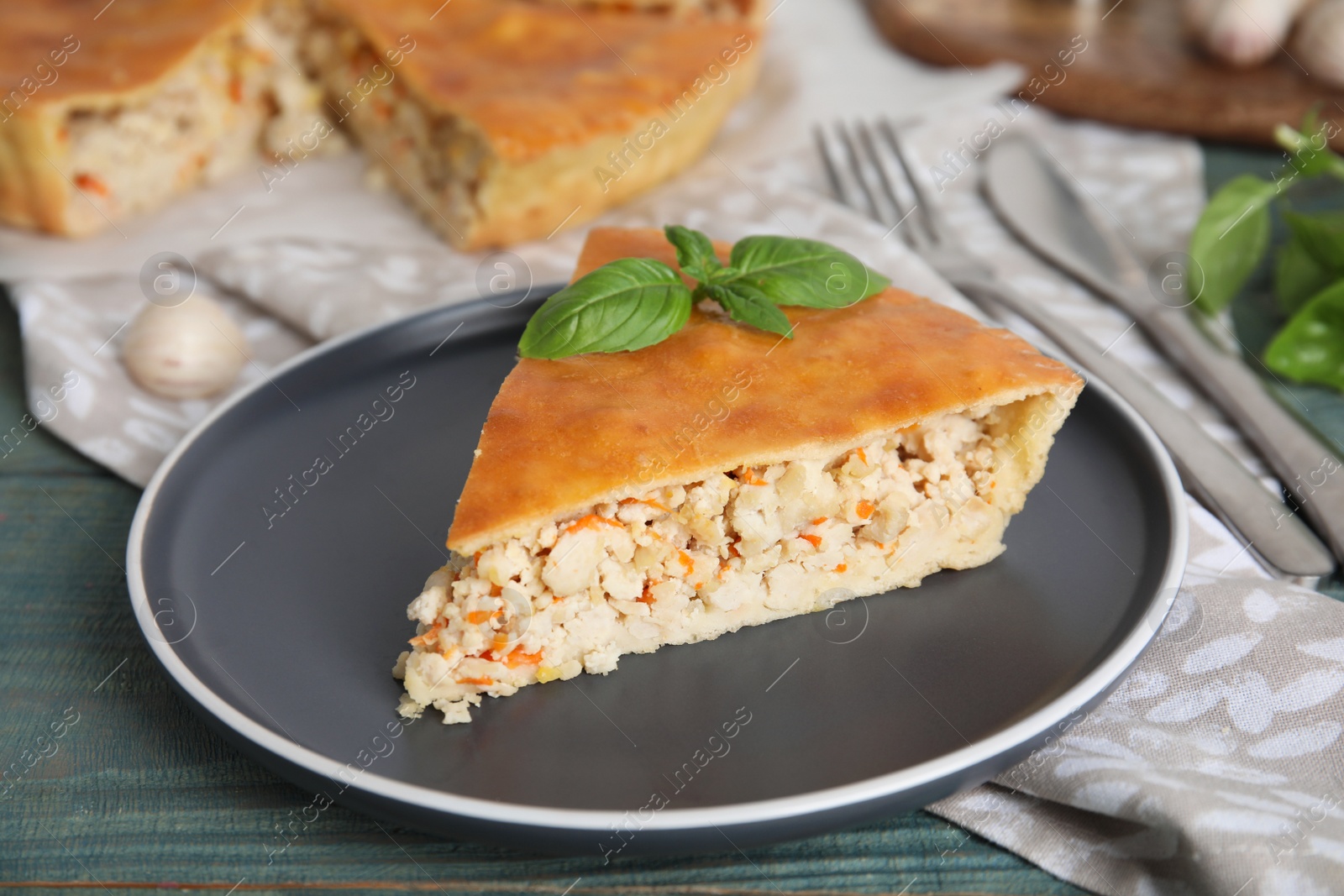 Photo of Slice of delicious meat pie with basil on blue wooden table
