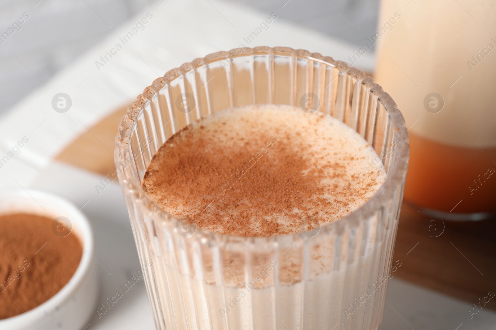 Photo of Delicious eggnog in glass on white table, closeup