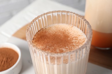 Delicious eggnog in glass on white table, closeup
