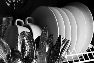 Photo of Set of clean wet tableware in dishwasher, closeup