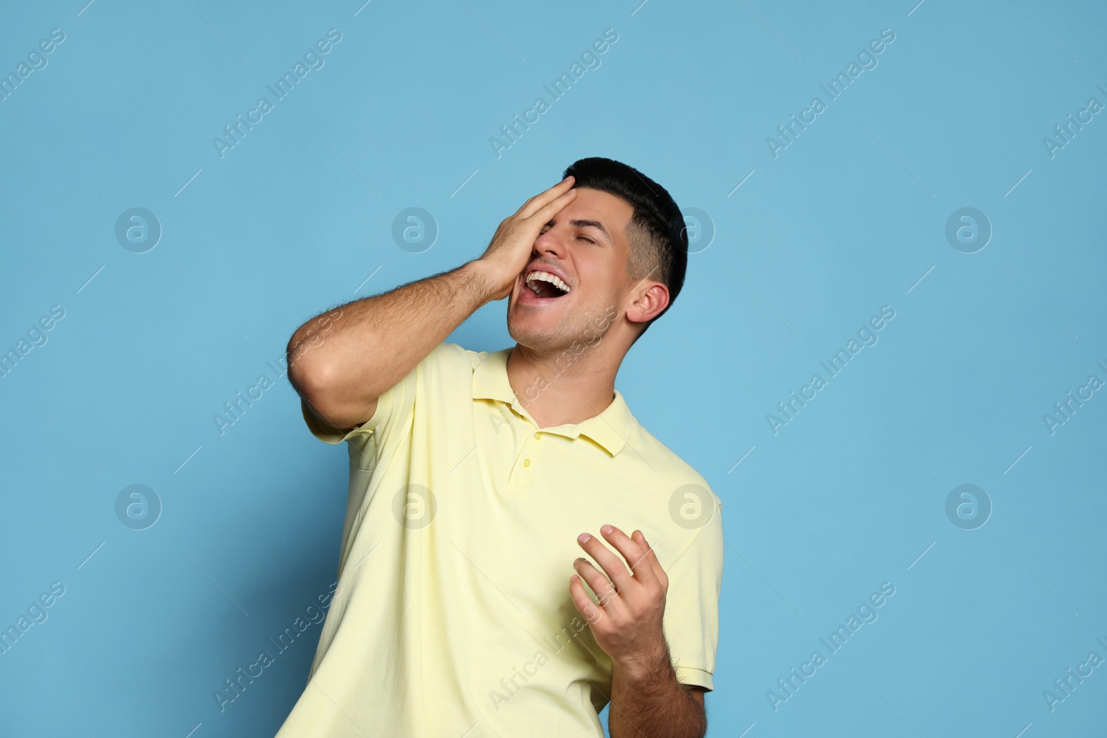 Photo of Handsome man laughing on light blue background. Funny joke