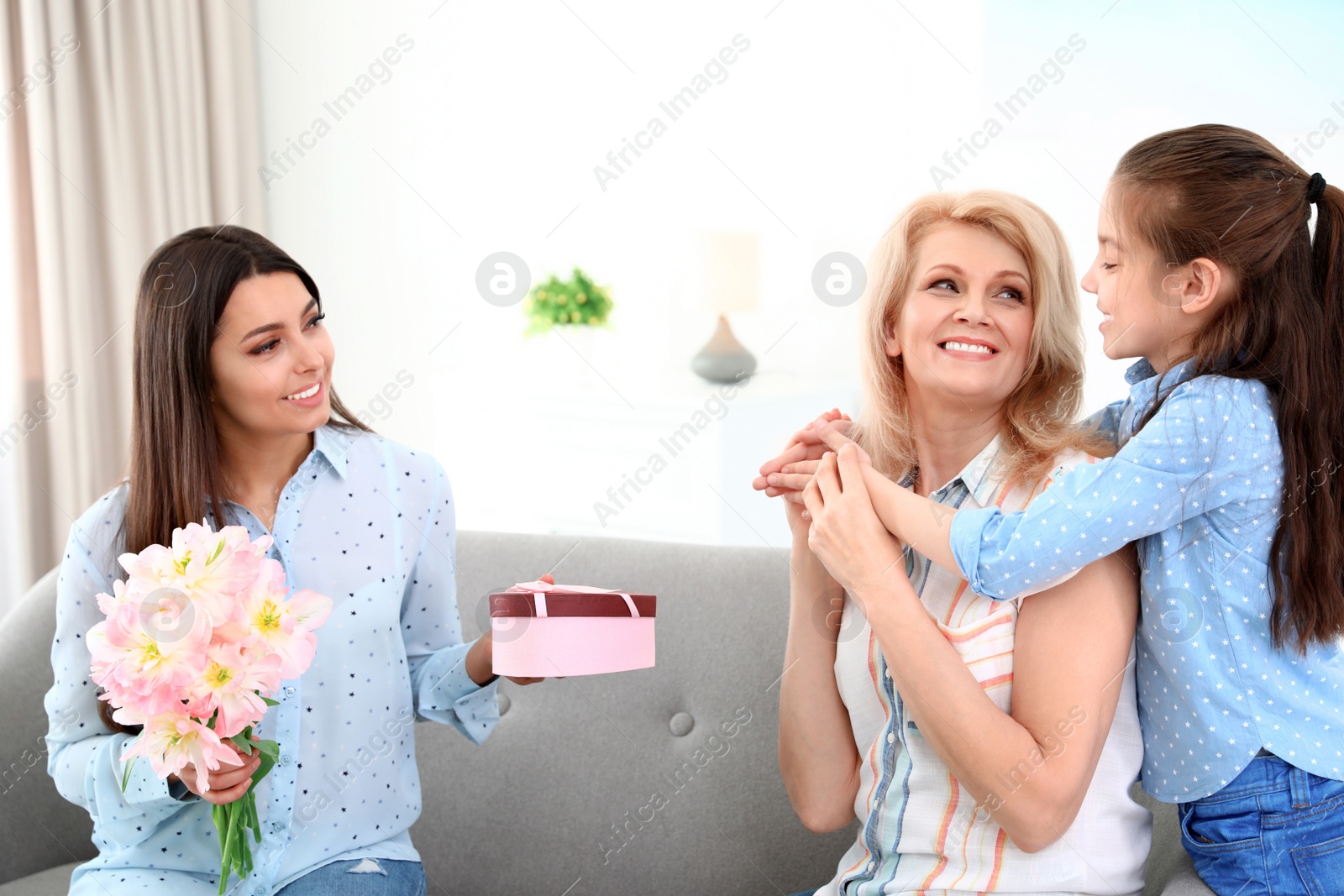 Photo of Woman and her daughter congratulating granny at home. Happy Mother's Day